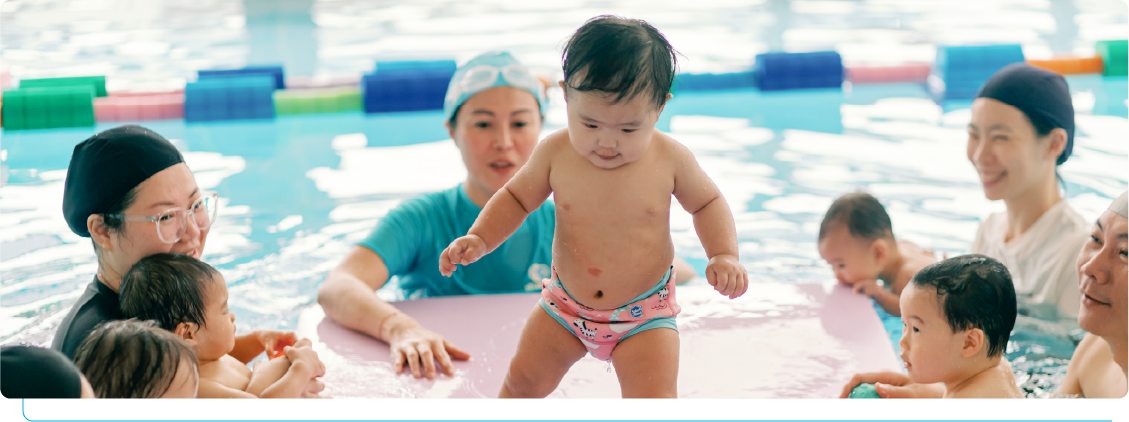 家長與老師在泳池陪伴嬰幼兒練習站立